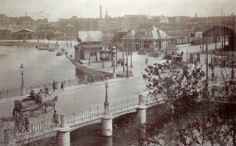 Tramstation van de Gooische Stoomtram aan het Rhijnspoorplein in 1913. Rechts een stukje van de kap van het Weesperpoortstation. .<br />Links de Singelgracht, middenachter de Amstelbrouwerij aan de Mauritskade.<br />Foto: Daar reed toen de Gooische. 