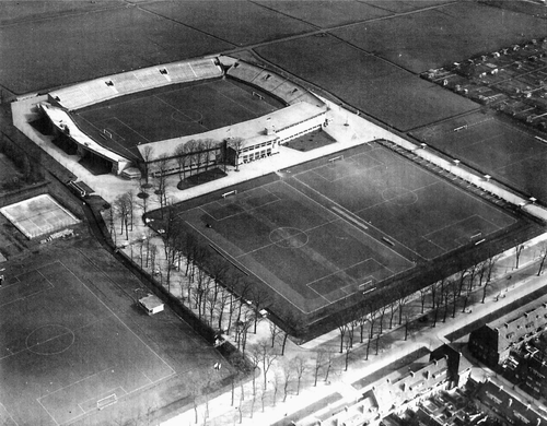 AJAX stadion 28-3-1936 Op deze luchtfoto uit 1936 is goed te zien dat de bomen op de oprijlaan bleven staan. 