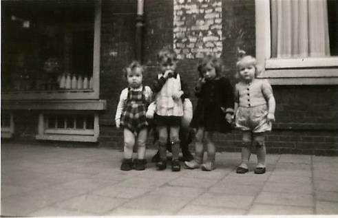Anneke geheel rechts voor de melkwinkel van Van der Vecht, haar tijdelijke pleegouders in de oorlog, omstreeks begin 1945. Zie de armoedige kleding, de schoenen en de kniebeschermers om de kousjes van de kinderen. Ook zo vlak na de oorlog was het nog 'armoe troef'.  .<br />Foto: Anneke Koehof 