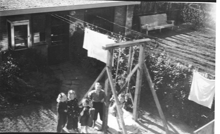  De tuin van buurvrouw tante Hetty, 1950. Vlnr. Anneke de Jong, Anita Schagen, Magdaleen en Herman van der Wusten en op de schommel hun zus Toos. 