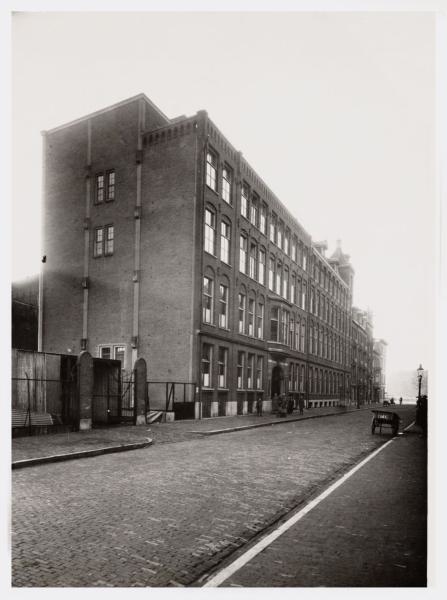 De Industrieschool 1n 1934 - Marcusstraat 2-54 (v.l.n.r.), gezien in oostelijke richting naar de Weesperzijde en de Amstel, met links op nummer 54 de Industrieschool voor Naaisters.<br />De foto is van (gemaakt door) Vereenigde Fotobureaux N.V. (fotograaf).<br />Bron: Beeldbank, Stadsarchief Amsterdam. 