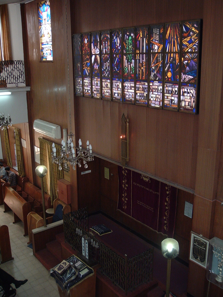 Interieur Israelische synagoge Nog eens de glas-in-loodramen in de synagoge in Israël, nu op een overzichtsfoto. Links is nog net een stukje hekwerk van de vrouwengalerij te zien, ook afkomstig van de synagoge aan de Linnaeusstraat (foto: Chaim Revier). 