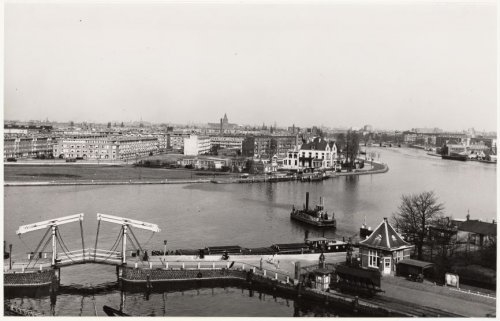 Korte Ouderkerkerdijk (met pontje). Het terrein van de Zuidergasfabriek, gezien naar de Amstel en de Amsteldijk. Op de voorgrond de haven en rechts de Omval. Foto gemaakt door: Rinus Knopper op 23 maart 1954. Bron: Beeldbank, SAA. 