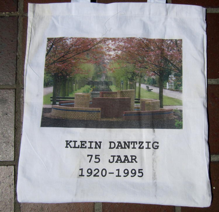 T.g.v. het 75 jaar bestaan van Klein Dantzig werd door Agnes van Genderen een stenen kunstwerk gemaakt, afgebeeld op dit tasje, wat qua vorm een beetje doet denken aan de oude fontein, die bij de ingang aan de Ringdijk stond. .<br />Foto: Jo Haen © 