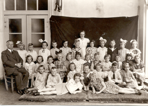 Eenhoorn KWschool Klassenfoto Koningin Wilhelmina school gemaakt omstreeks  1937.<br /><br />Zittend op de stoel het hoofd van de school, de heer D. van Vliet en staand midden achteraan juffrouw Helena van Vliet.<br /><br />Henny (met strik)  staat rechts naast het schoolhoofd.<br />Nog een paar namen: Otto Tho-mas (staat voor juffrouw van Vliet), Gerben Baaij (zit links voor Otto), Janny Thomas (het tweede meisje rechts naast juffrouw van Vliet, Rietje Rakers (liggend links vooraan) en Jopie Prins (liggend rechts vooraan). Jopie is een dochter van de andere melkboer Prins ( winkel op de hoek van de Ringdijk en de W. Beukelsstraat.) 