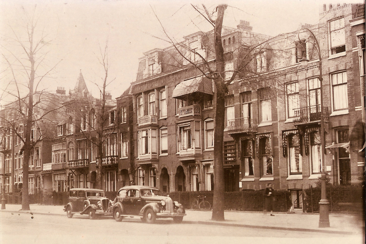 Middenweg 131 is 2e huis vanaf rechts  - ± 1930 .<br />De auto is van dokter Doets.<br />Foto: Jan van Deudekom 