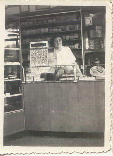 Moeder Verdooner in de winkel aan de Tugelaweg. Moeder Jetje Verdooner-de Lara achter haar toonbank, altijd even keurig gekleed en klantvriendelijk. De foto is afkomstig uit het fotoarchief van David Verdooner. 