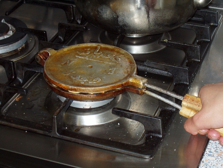 Koekjespan in gebruik5 Dan worden de deegballetjes gebakken op een vuurtje (of fornuis). 