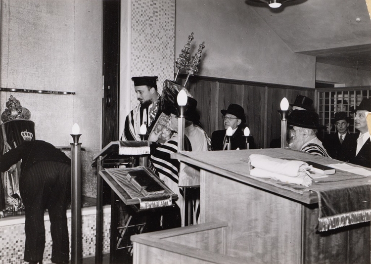 Inwijding! De Torarollen worden in de ark geplaatst tijdens de inwijding van de nieuwe synagoge aan de Linnaeusstraat 107 (in 1956). Links van de Torarol de opperrabbijn: A. Schuster. Bron: fotoarchief NIW, via het JHM. 