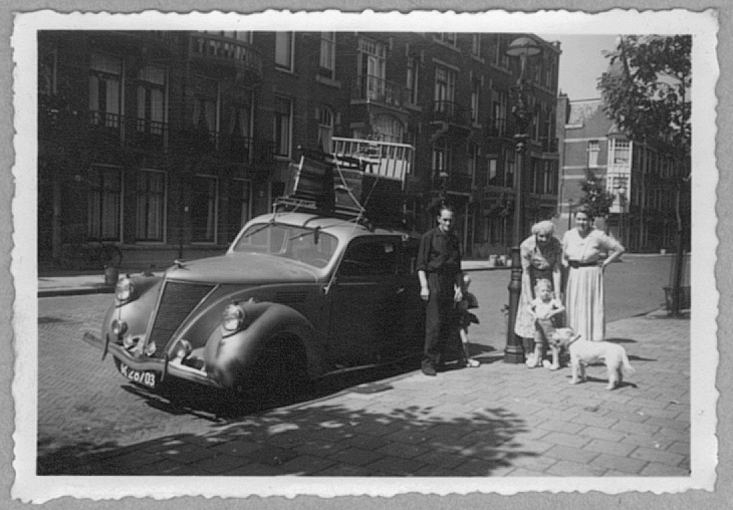 Op vakantie Op vakantie (1953): zelf hadden wij geen auto. Hier worden we door een vriend - met wel zo’n rijk bezit — opgehaald om op vakantie naar Egmond aan Zee te gaan. De box gaat bovenop. Mijn oma en mijn moeder staan naast de auto, die verder in een nog lege straat staat te wachten. 