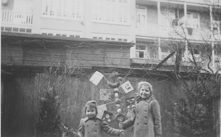  Lia en haar oudere zusje Hans in de tuin van hun huis, Pretoriusstraat 48.<br />'Mijn moeder bestelde de haasjes bij de bakker en wij versierden ze met glimmende melkdoppen, die we tot lange slingers regen. Met onze palmpasen gingen we trots naar school. En daarvandaan gingen we in optocht door de buurt. 