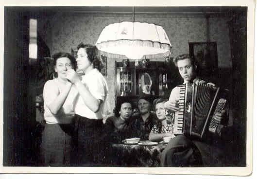  'Een gezellig avondje thuis' in 1952: oma en moeder Coby Jansen dansen met elkaar, vader Jan speelt op de accordeon. 