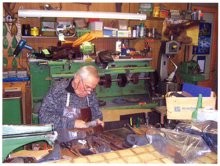 Schoenmaker Herman aan het werk Met op de voorgrond de leersnijmachine die zijn vader nog met Marshall hulp heeft verworven vlak na de oorlog. Foto gemaakt in november 2009. 
