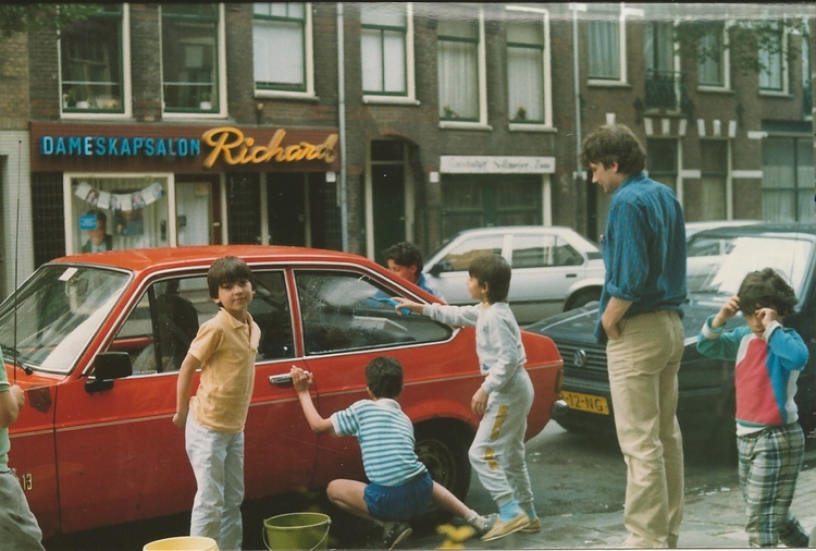 Foto gemaakt vanaf Vrolikstraat 120 hs, Ton Kok poetst de auto met de buurkinderen.  
