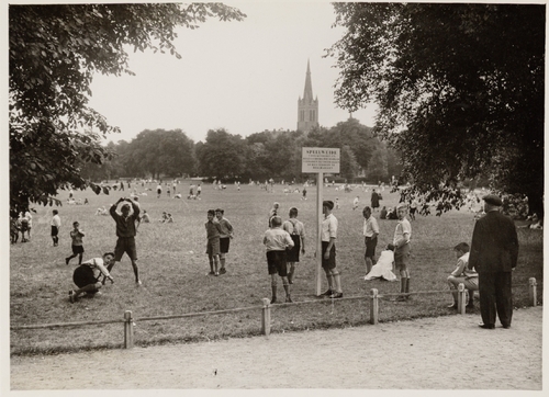 Speelweide Oosterpark.  Speelweide in het Oosterpark met spelende schoolkinderen en in het verschiet de toren van de rooms-katholieke Sint Bonifatiuskerk (Kastanjeplein). Datering: juli 1932, bron: beeldbank SAA.  