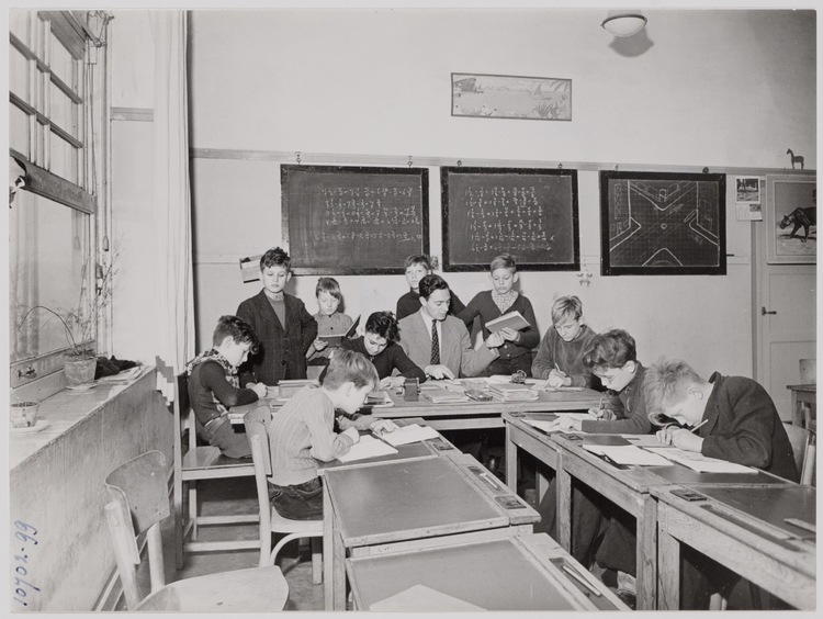 Drukte rondom de tafel van onderwijzer Wim Meijer jaren 50 - Foto: Beeldbank Amsterdam  