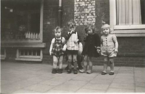 Anneke (rechts) voor de melkzaak van haar pleegouders uit de oorlog, w.s. rond 1945. Wie goed kijkt ziet dat er nog een kindje achter zit. Vreemd is dat alle vier de kindertjes een soort kniebeschermers dragen, kennelijk in deze moeilijke tijden om de kousjes te beschermen (?) eigen foto  