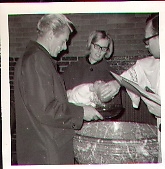 Doop door Andre Tonis 1967. Kapelaan Tönis doopt Marco Battarino. Links dhr.René Koller (peter) en naast hem Jo Haen (meter). 