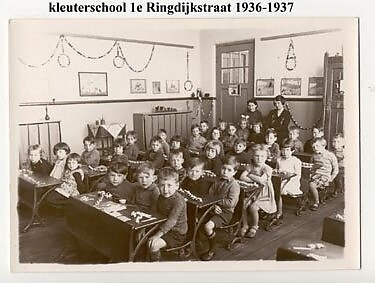  De kleuterschool aan de 1e Ringdijkstraat met juffrouw van Weezel (rechts) en assistent (links). Foto opgestuurd door Dolf de Bie (1930) die in het derde bankje zit aan de muurzijde<br />Ik zit in het derde bakje muurzijde. Zie ook zijn reactie onderaan dit verhaal. 