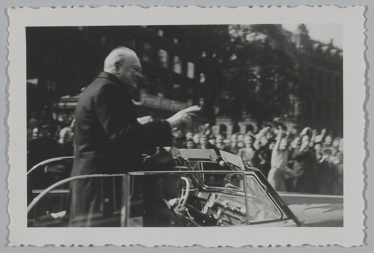 Sir Winston Churchill in een open auto op de Nieuwezijds Voorburgwal ter gelegenheid van de ontvangst door koningin Wilhelmina in het Koninklijk Paleis in een open auto op de Nieuwezijds Voorburgwal ter gelegenheid van de ontvangst door koningin Wilhelmina in het Koninklijk Paleis<br />8 mei 1946 <br />Foto: Beeldbank Amsterdam 