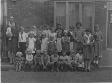Omstreeks 1939 voor het huis gefotografeerd. De 5e jongen van rechts met z warte broek is broer Bertus (1933), het meisje met de strik is zus Jannie en daarnaast Pietertje met de hand op schouders van meisje voor haar.  
