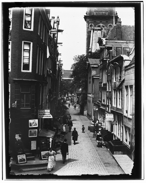 Foto van Zandstraat 17-27 (rechts) (v.l.n.r.), gezien vanaf Sint Antoniesbreestraat naar Kloveniersburgwal. Datering 24 juni 1896, gemaakt door Jacob Olie, collectie SAA  